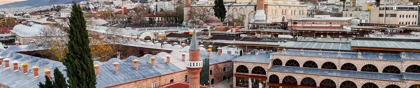 Historic mosque and bustling bazaar district in Bursa, Turkey, with mountain backdrop at sunset