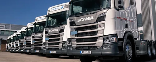 a-fleet-of-scania-semi-trucks-parked-in-a-row-displaying-the-companys-logo-on-the-front-the-trucks-are-predominantly-white