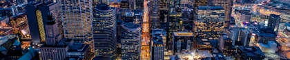 Aerial view of Minneapolis skyline at dusk with illuminated skyscrapers and city lights