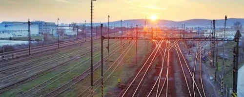Expansive railway network with multiple tracks and overhead power lines at sunset, illustrating rail freight infrastructure.