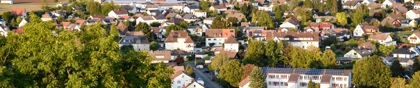 Aerial view of Gudensberg, Germany, showcasing a small town with red-roofed houses, green landscapes, and rolling hills in the background