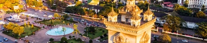 Patuxai Monument in Vientiane, Laos, surrounded by gardens and city buildings at sunset