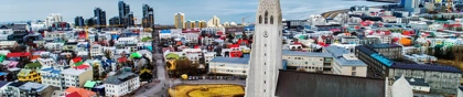Hallgrímskirkja church overlooking Reykjavik, Iceland, with colorful buildings and a snowy mountain range in the background