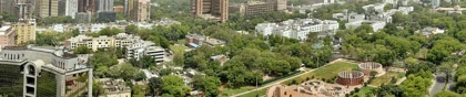 Panoramic cityscape of New Delhi, India, featuring Jantar Mantar observatory surrounded by greenery and modern buildings.