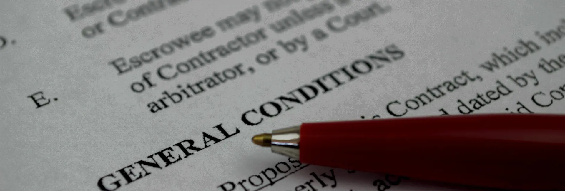 Close-up of a document with the heading 'General Conditions' and a red pen pointing to the text