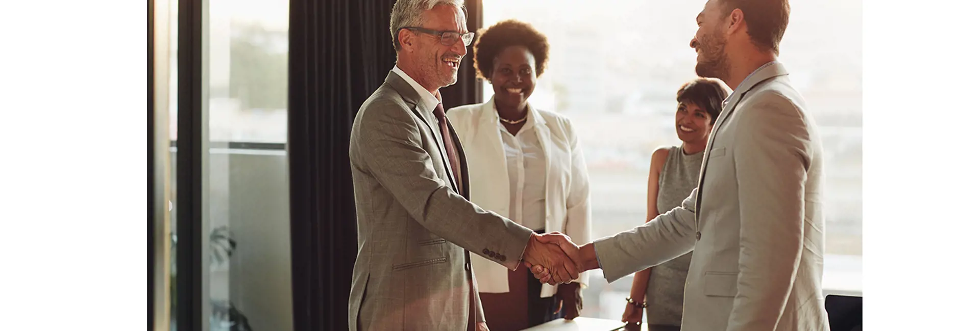 Professionals shaking hands in an office, symbolizing business integrity and Scan Global Logistics' commitment to their four virtues