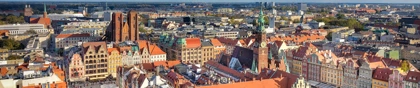Colorful historic buildings surround the Market Square in Wrocław, Poland, under a bright blue sky