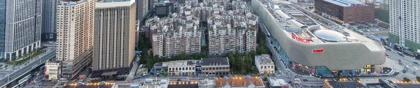 Wuhan cityscape with modern high-rise buildings, a large shopping complex, and riverside architecture at sunset
