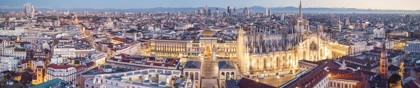 Panoramic evening view of Milan, showcasing the illuminated Milan Cathedral (Duomo di Milano) and surrounding cityscape