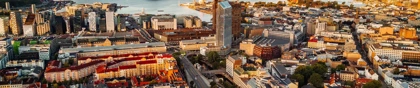 Panoramic aerial view of Oslo, Norway, showing the city skyline, modern architecture, and Oslofjord in the background at sunset